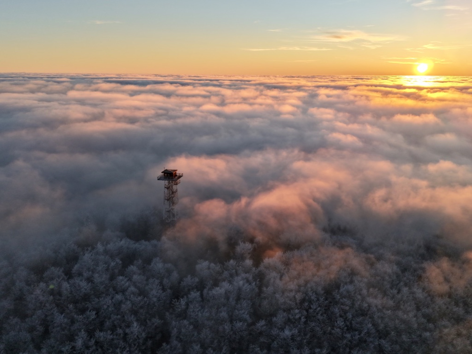 Feuerwachturm ragt aus einem dichten Nebelmeer bei Sonnenaufgang