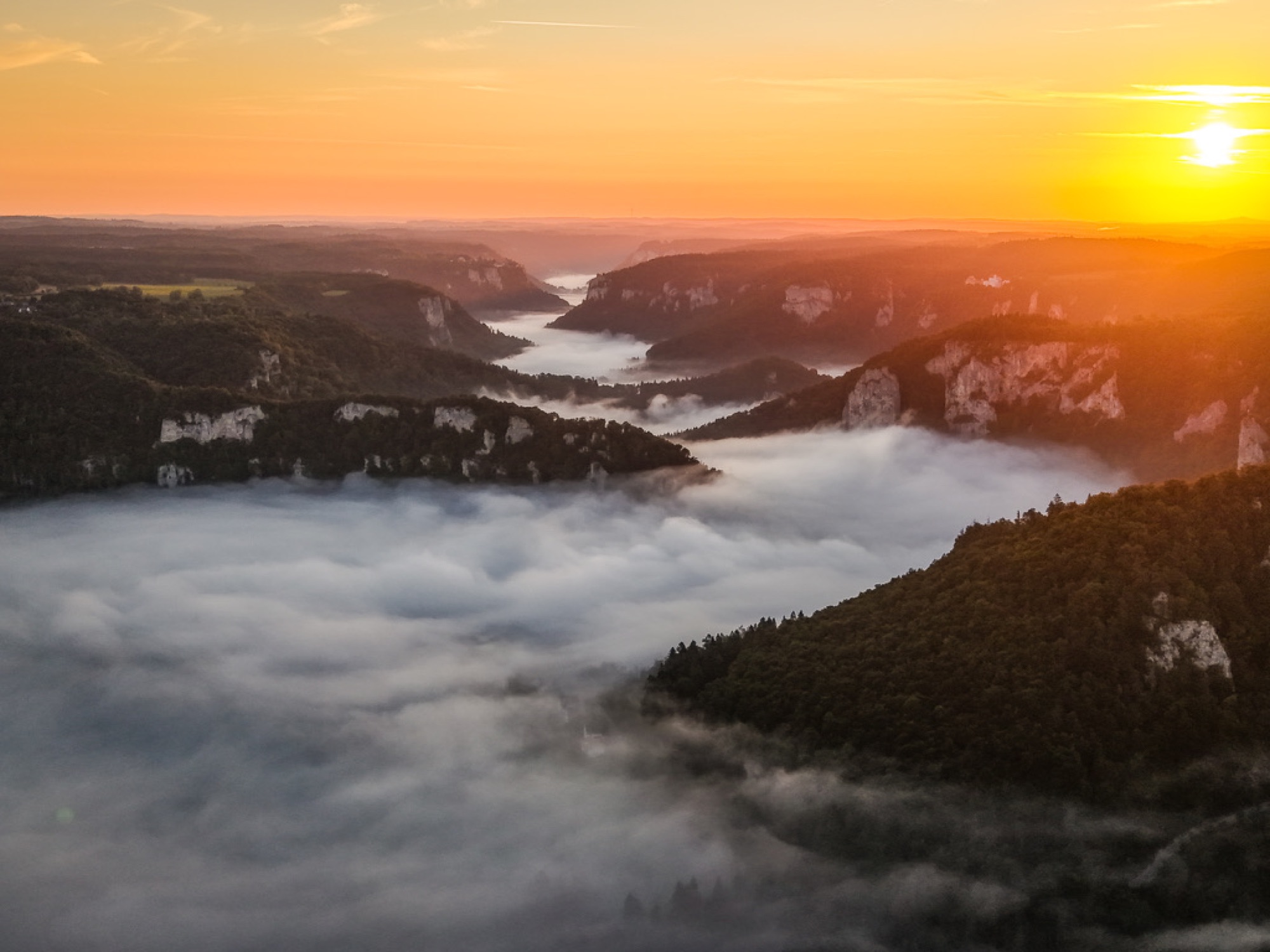 Nebelverhangenes Flusstal mit Felsformationen im Sonnenuntergang