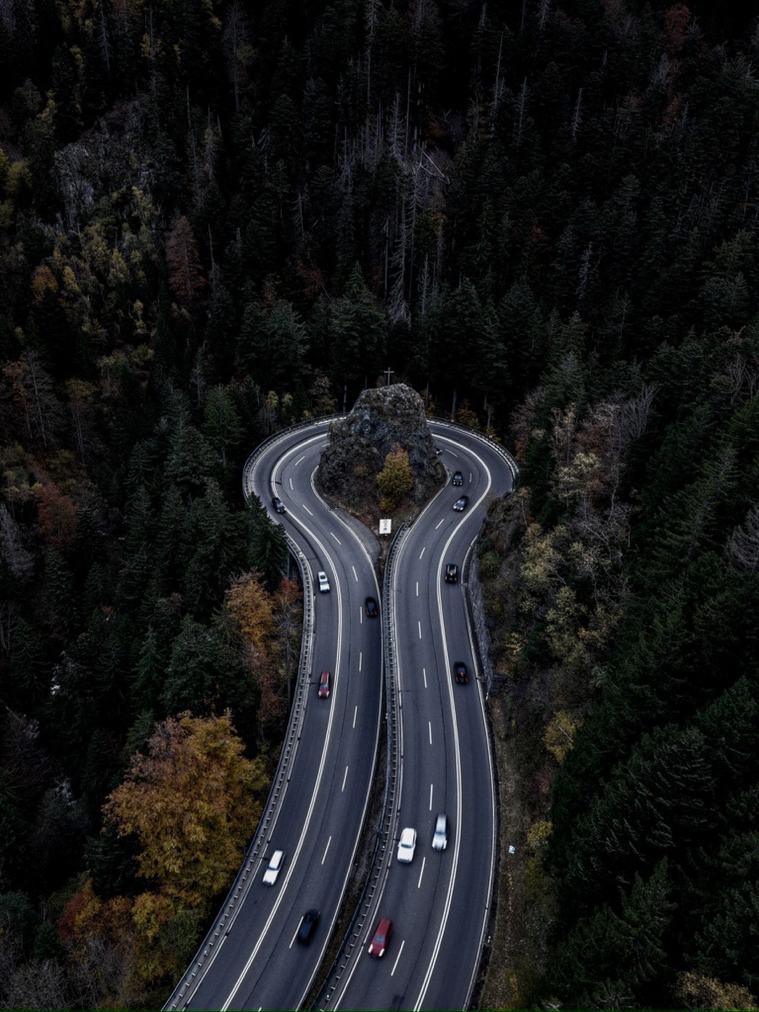 Serpentinenstraße durch den Wald mit markantem Fels in der Kurve
